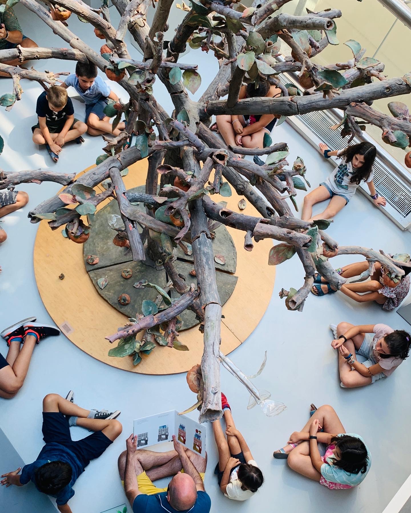 albero in ceramica con bambini seduti in cerchio sotto 