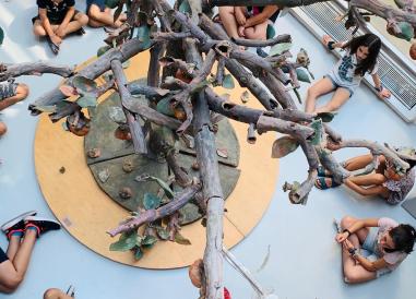 albero in ceramica con bambini seduti in cerchio sotto 